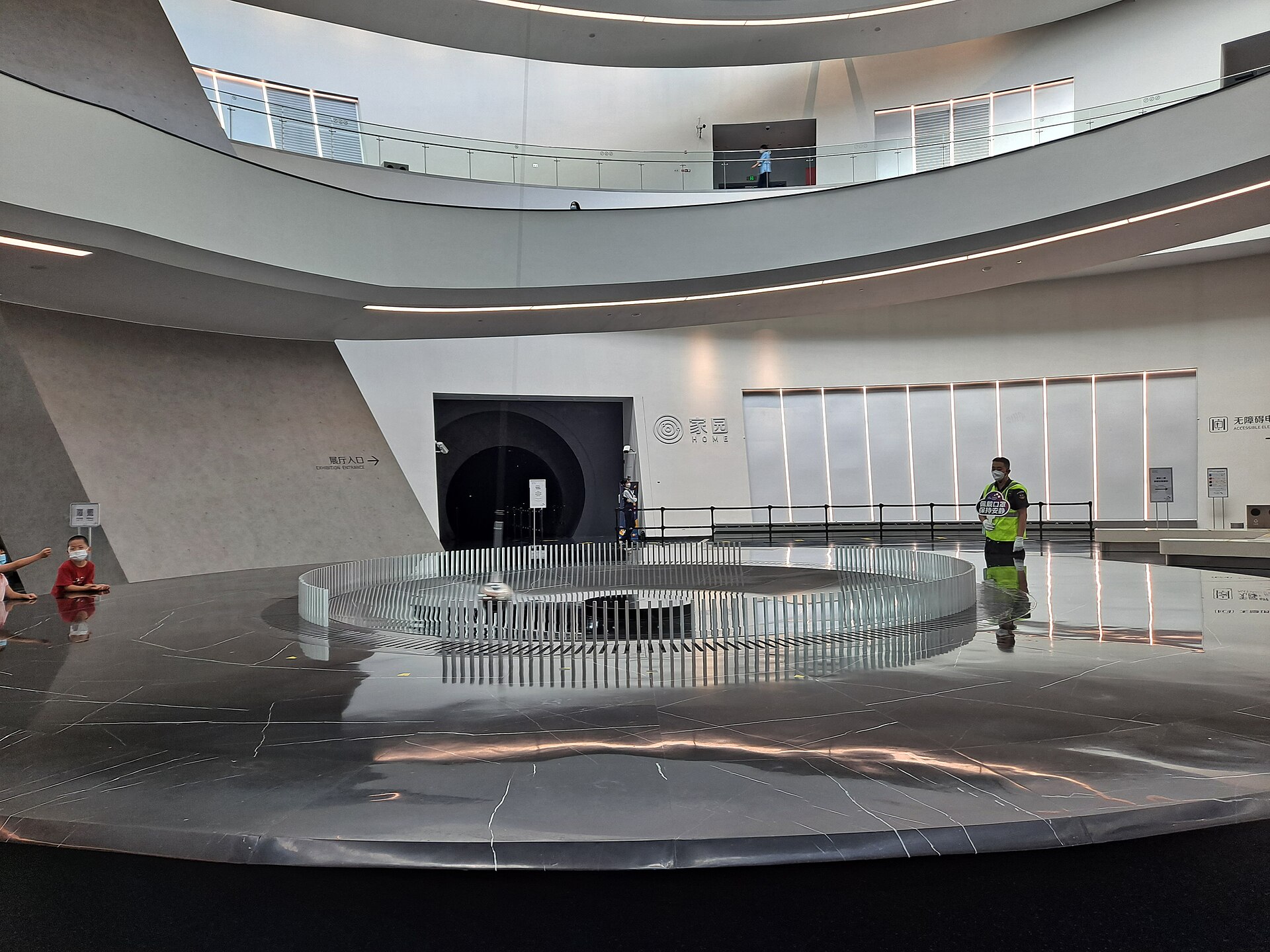 A Foucault pendulum above a circular base inside a bright, curved white hall at the Shanghai Astronomy Museum