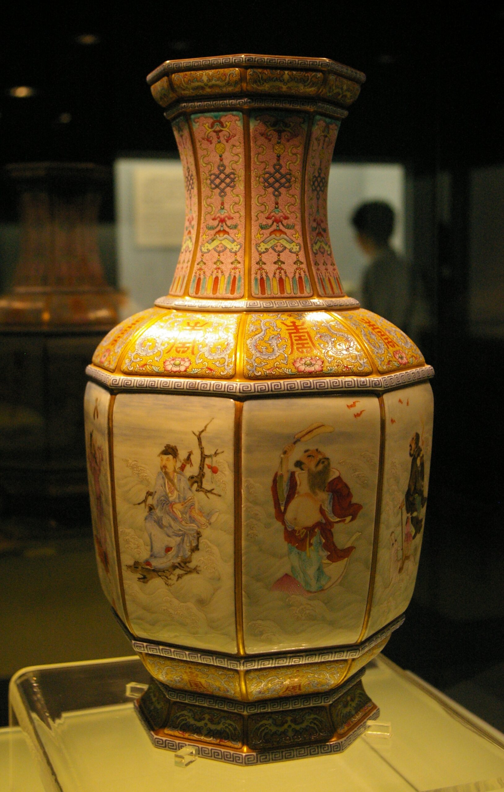 A Qing dynasty porcelain vase painted with figures of the Eight Immortals in a glass display case