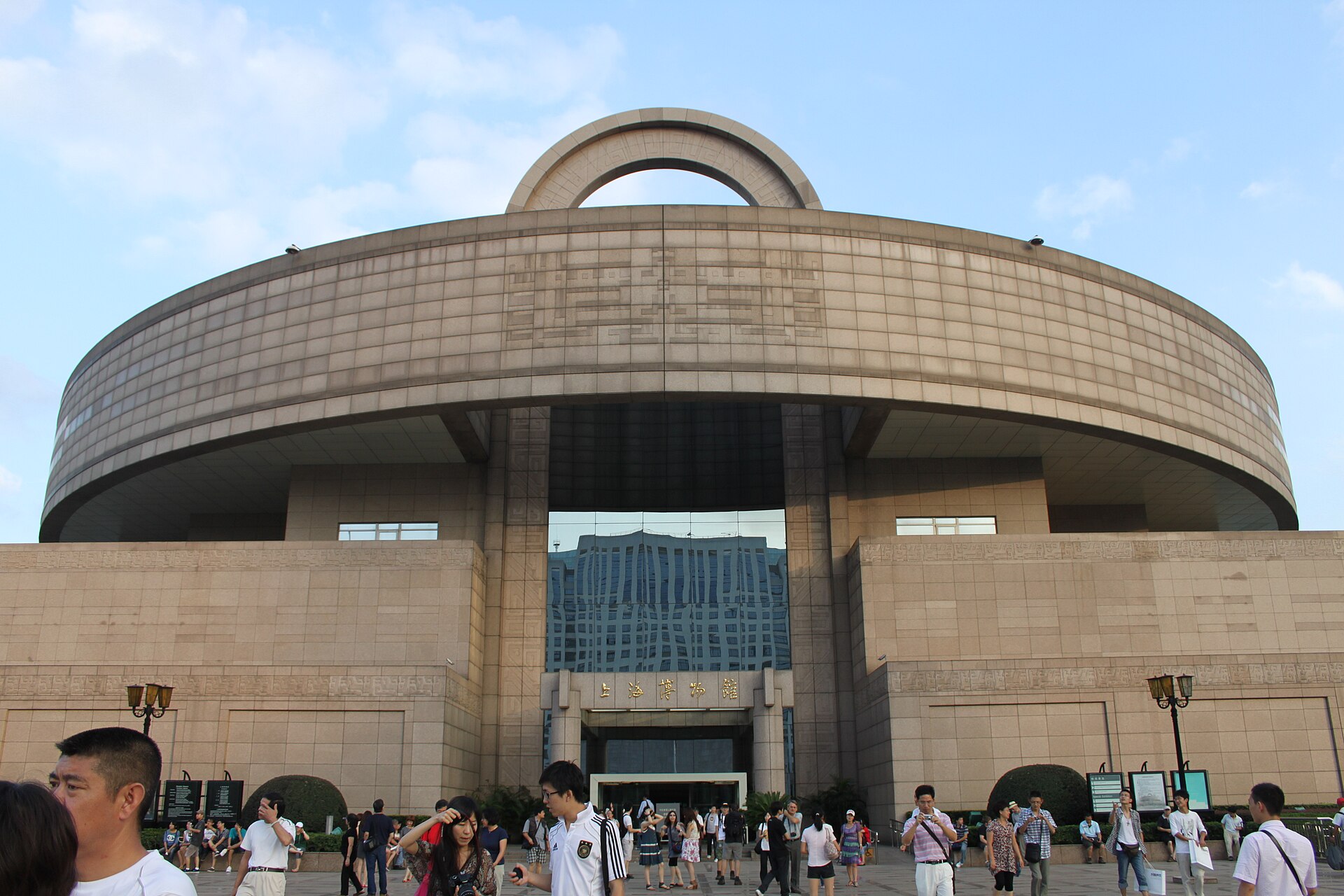 The circular stone Shanghai Museum building on People's Square, with its arched top and visitors on the plaza in front